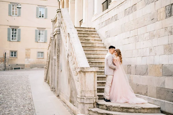 Abrazando a los recién casados de pie en las escaleras de un antiguo edificio en Bérgamo, Italia —  Fotos de Stock