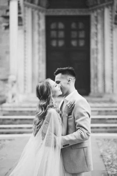 Pelukan pengantin pria dan ciuman mempelai wanita dengan latar belakang pintu masuk ke Basilika Santa Maria Maggiore, Roma, Italia. Foto hitam dan putih — Stok Foto