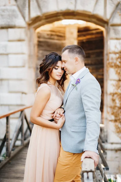 Doucement embrasser mariée dans une belle robe tout en se tenant sur le pont menant au château — Photo