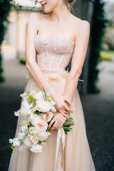 Mariée souriante dans une belle robe aux épaules nues tenant un bouquet de fleurs roses — Photo