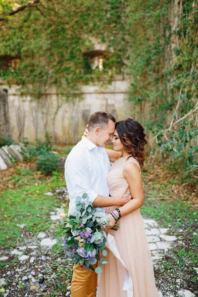 Groom étreint mariée dans une robe pastel sur le fond d'un entrelacé avec mur de pierre de lierre — Photo