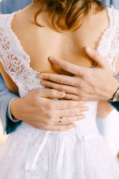 Damadın yakın çekim elleri beyaz dantelli elbiseyle gelini belinden kucaklıyor.. — Stok fotoğraf