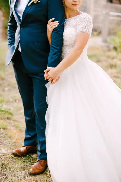 Bruden och brudgummen står omfamna, bruden håller brudgummen hand och försiktigt kramar — Stockfoto