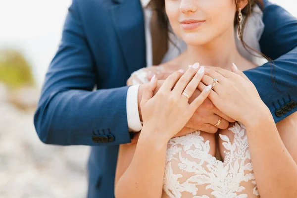 A vőlegény óvatosan átöleli a menyasszonyt a vállánál fogva, a menyasszony ráteszi a kezét a vőlegény karjára, közelről. — Stock Fotó