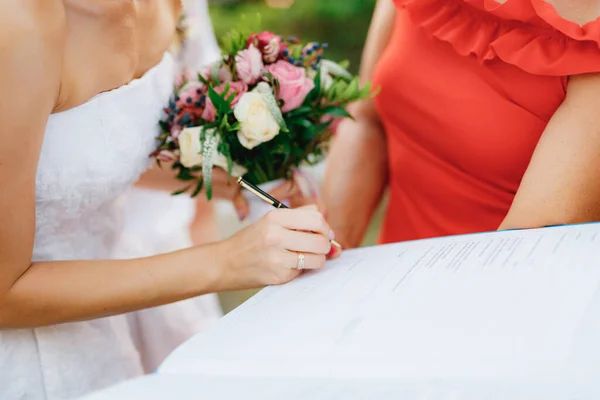 Die Braut unterschreibt die Hochzeitsurkunde während der Trauung, Nahaufnahme. — Stockfoto