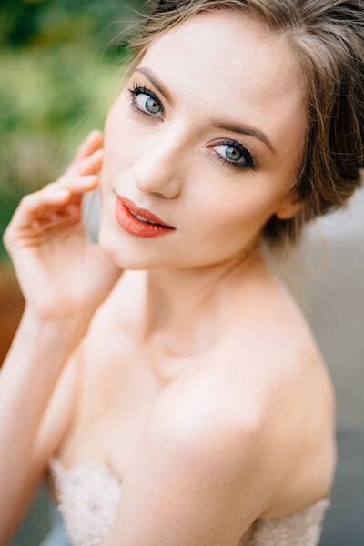 Pensive bride in a beautiful dress put her hand on her cheek. Portrait