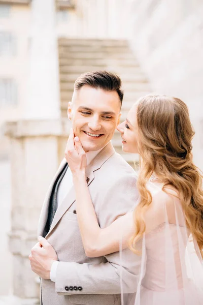 Novia sostiene su palma en la barbilla del novio sonriente sobre el fondo de los escalones de un antiguo edificio en Bérgamo —  Fotos de Stock