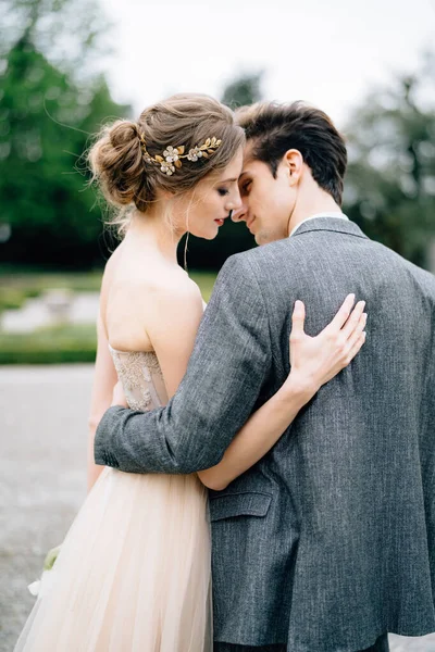 Groom hugs and almost kisses bride in the park. Lake Como, Italy — Stock Photo, Image