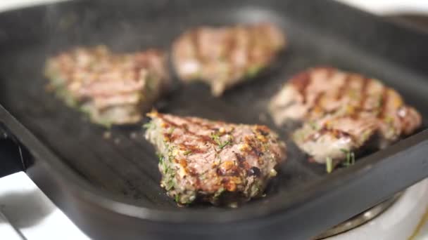 Vier geroosterde steaks op een gegrilde pan, met fijn gesneden rozemarijn. — Stockvideo