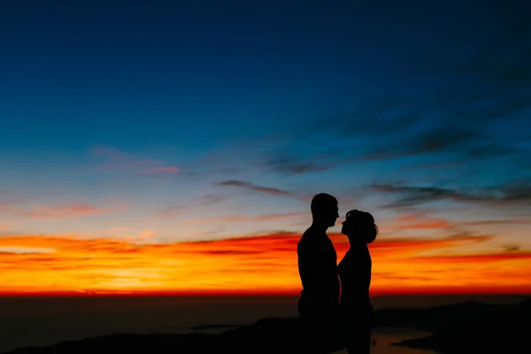 在落日落山的背景下，一对情侣手牵手的轮廓。靠近点 — 图库照片