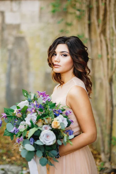 Cantik pengantin dalam gaun krim dengan karangan bunga mawar di tangannya — Stok Foto