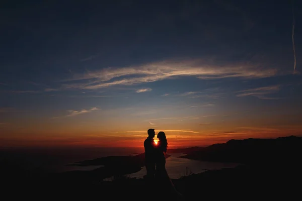 Silhouette degli sposi che si stanno abbracciando sul Monte Lovcen con vista sulla baia di Kotor al tramonto — Foto Stock