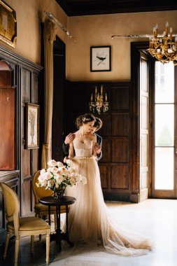 Damat, gelini masanın arkasından eski bir villada bir buket gülle kucaklıyor. Como Gölü