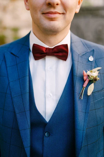 Усміхнений наречений у блакитному костюмі з трьома частинами та білою сорочкою з червоною краваткою та бутоньєрою — стокове фото