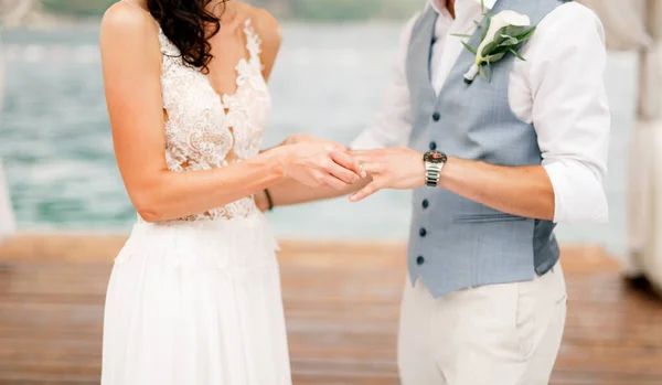 La mariée met l'alliance sur le doigt du marié pendant la cérémonie de mariage au bord de la mer — Photo