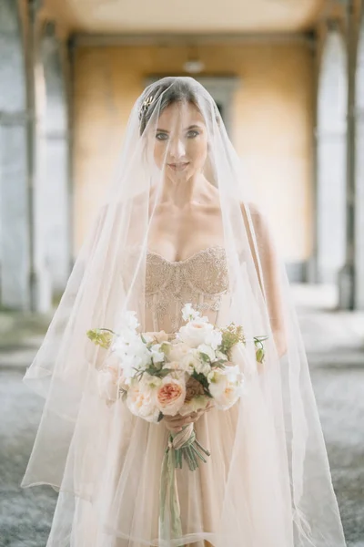 Pengantin dalam gaun pengantin dan kerudung dengan buket di teras tua dengan kolom. Danau Como — Stok Foto