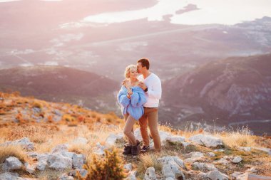 Adam, Karadağ 'ın Kotor Körfezi' ndeki Lovcen Dağı 'nın arka planında mavi kazaklı bir kadına sarılıyor. Kapat.