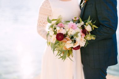 Gelin ve damat güzel bir buket çiçek tutuyorlar.