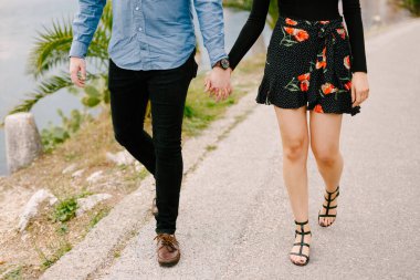 Yol boyunca el ele tutuşan bir çift yürüyor. Kapat.