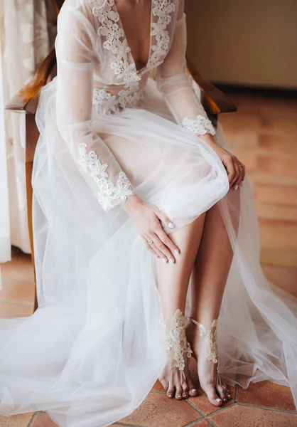 Braut im weißen Hochzeitskleid barfuß auf Stuhl sitzend — Stockfoto