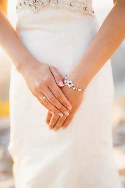 De bruid vouwde haar handen met een trouwring om haar vinger en een armband, close-up — Stockfoto