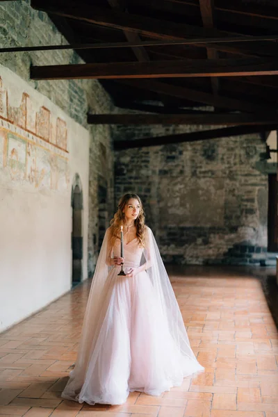 Novia con una vela en sus manos camina a lo largo de una logia en una antigua villa en el lago de Como —  Fotos de Stock