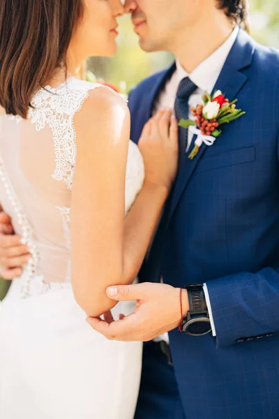 Наречений в блакитному костюмі обіймає наречену в білій мереживній сукні — стокове фото