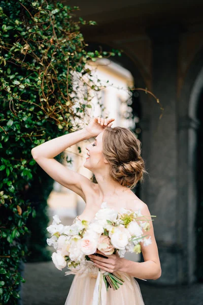 A noiva em um vestido rosa com um buquê de flores colocou sua mão na testa em um fundo de plantas verdes. Lago de Como — Fotografia de Stock