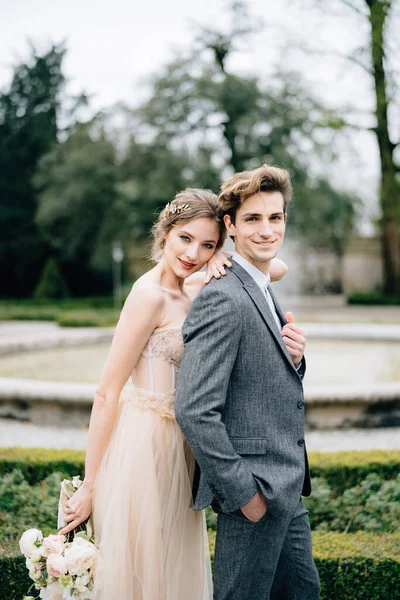 La novia apoyó su cabeza en el hombro del novio, abrazándolo por detrás, frente a la fuente. Lago de Como, Italia. De cerca. —  Fotos de Stock