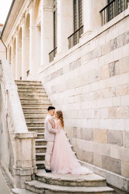 Damat ve gelin, İtalya 'nın Bergamo kentindeki eski bir binanın merdivenlerinde duruyor.