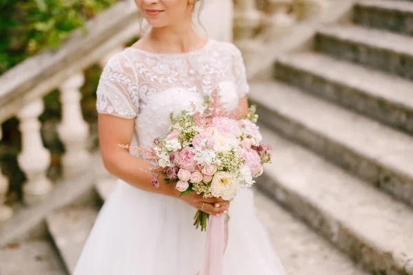 Skonsam brud med en bröllopsbukett i händerna stående på den antika trappan i templet i Prcanj — Stockfoto