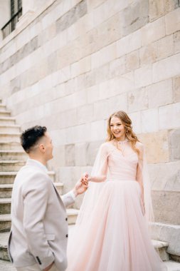Gelin ve damat, İtalya 'nın Bergamo kentindeki antik bir binanın merdivenlerinde el ele tutuşuyorlar.