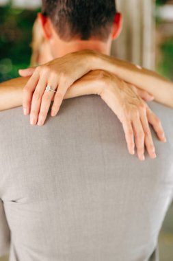 Gelin ve damat sarılır, gelin kollarını damadın omuzlarına dolayar, yakın plan. 