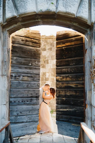 Sposa abbracci sposo mentre in piedi dietro la porta aperta in legno del castello — Foto Stock