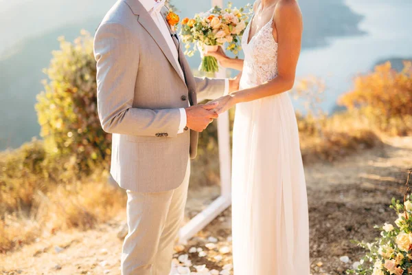 Gli sposi sono in piedi sul Monte Lovcen vicino all'arco nuziale e si tengono per mano — Foto Stock