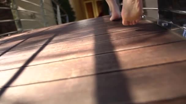 Femme pieds nus court le long d'une terrasse en bois dans un peignoir flottant — Video
