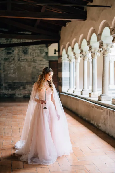 Novia con una vela encendida en sus manos se levanta y mira al suelo de la logia en una antigua villa en el lago de Como —  Fotos de Stock