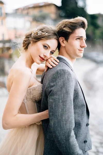 Épouses pensives câlins marié par derrière tout en se tenant sur la promenade du lac de Côme — Photo
