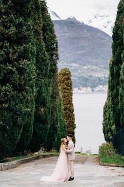 Yeni evliler, İtalya 'nın Como Gölü' nün arka planına karşı bir zeytin koruluğunda birbirlerine sarılıyorlar.