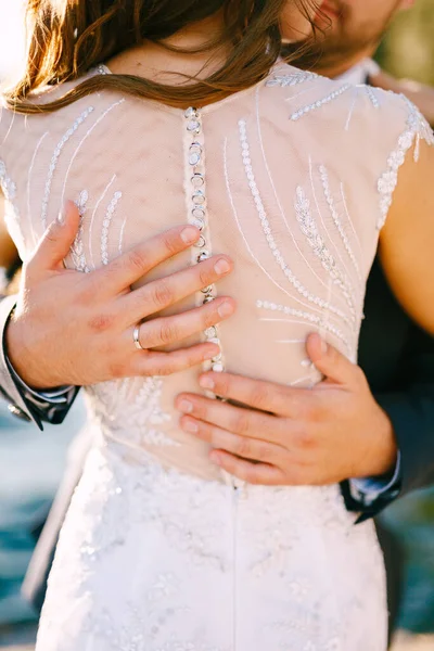 A vőlegény gyengéden átöleli a menyasszonyt egy gyönyörű fehér esküvői ruhában. — Stock Fotó