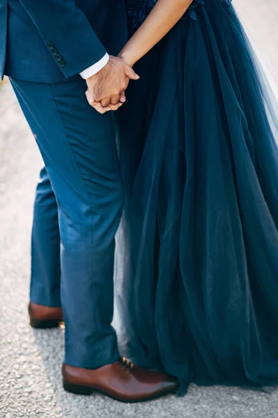 El novio en el traje azul toma la mano de la novia en el vestido azul. De cerca. Vista inferior —  Fotos de Stock