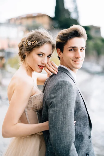 Sonriente novia abraza novio por detrás, mientras que de pie en el paseo marítimo del Lago de Como. —  Fotos de Stock