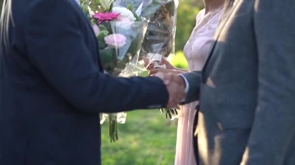 Чоловік трясе руки нареченому і дарує букет квітів нареченій на весіллі — стокове відео