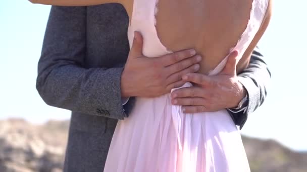 Der Bräutigam umarmt die Braut und streicht sanft über ihren offenen Rücken, Nahaufnahme — Stockvideo