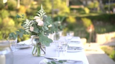 Bir düğün ziyafetinde, bir buket gül, astilba, Cortaderia ve okaliptüs dalları bir şenlik masasındaki kavanozlarda.