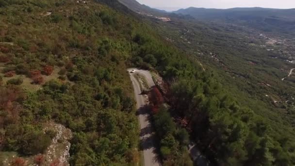 Valkoinen avoauto ratsastaa pitkin viehättävä vuori käärme Mount Lovcen — kuvapankkivideo
