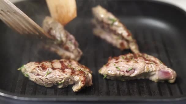 Lo chef sta girando i pezzi di bistecca tostata in una padella. — Video Stock