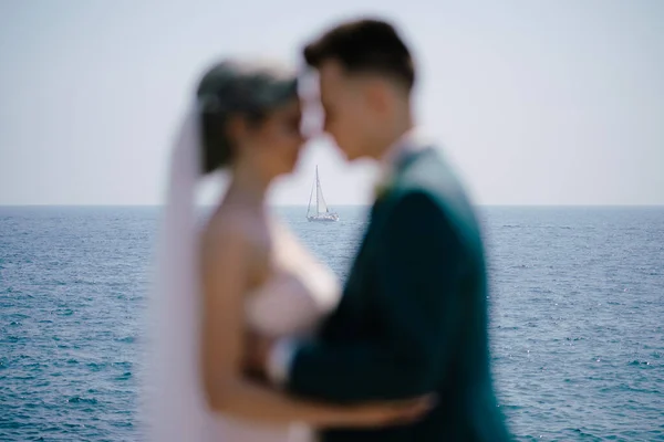 Silhuetas de abraçar recém-casados no fundo de um iate branco à vela em mar aberto — Fotografia de Stock