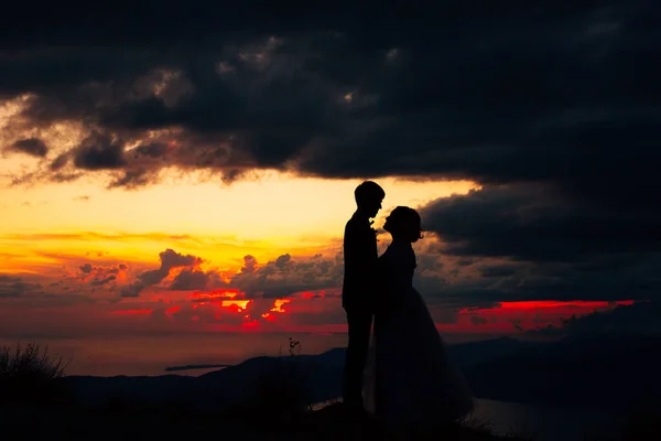 新娘和新郎在黄昏时手牵手站在海滨的轮廓 — 图库照片