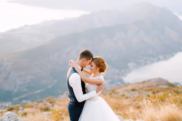 Les mariés se tiennent debout sur le sommet du mont Lovcen surplombant la baie de Kotor et embrassent tendrement, gros plan — Photo